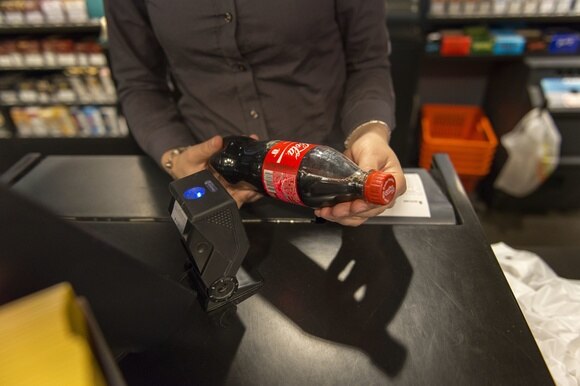 persona alla cassa scannerizza una bottiglietta di coca cola