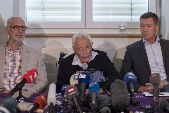 tre uomini seduti a un tavolo dietro a dei microfoni