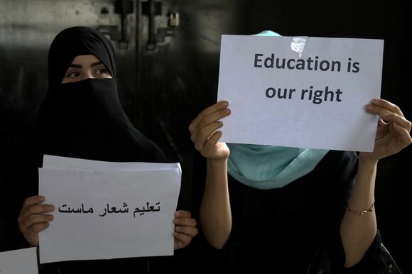 due donne con velo integrale tengono due cartelli in arabo e in inglese con scritta l educazione è un nostro diritto