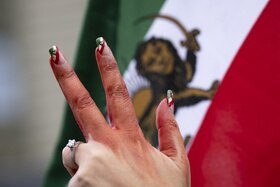 tre dita di donna con bandiera iraniana sulle unghie alzate ins egno di protesta