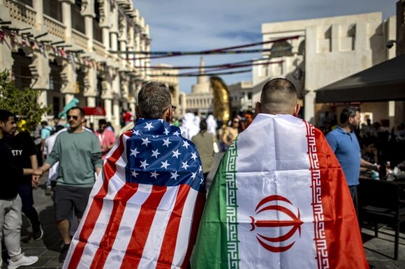 Due tifosi fotografati di spalle a Doha, uno con la bandiera USA e l atro con quella iraniana.