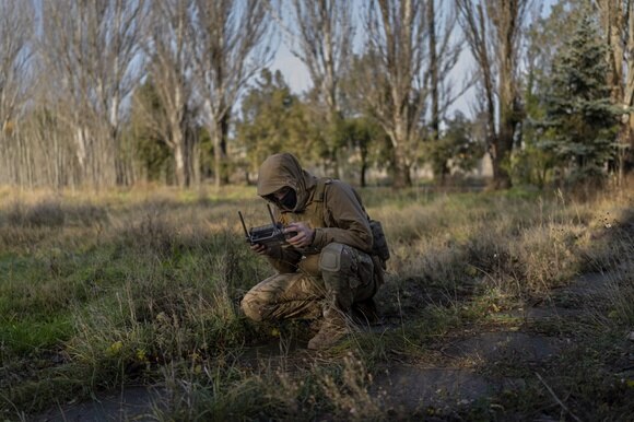 soldatoin tenuta mimetica accovacciato per terra verifica telecomando del drone