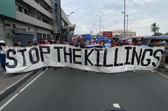 corteo di persone con, di fronte, striscione con scritta stop the killings