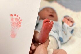 piedino di neonato risoperto di inchiostro rosso e impronta rossa su un foglio