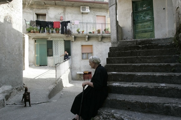 donna anziana seduta su una scala con un cane nei paraggi