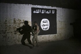 Un soldato passa davanti al murale dello Stato Islamico