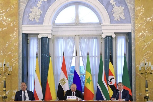 putin e leader africani seduti a tavolo con bandiere di diversi paesi dietro di loro