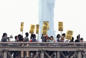 Manifestazione in difesa dei migranti sotto la statua della libertà a New York.